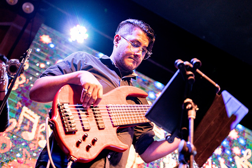 Musician man playing electric bass while use digital tablet in a music concert