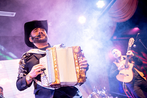 Musician man playing accordion while sing in a music concert