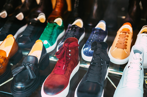 A selection of colorful leather brogues and shoes on display in a shoe shop window.