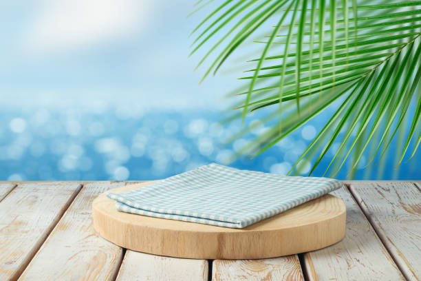 istock Empty wooden podium with tablecloth on table over tropical beach bokeh background.  Summer mock up for design and product display. 1491728493
