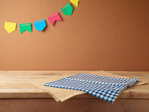 Brazilian Festa Junina summer harvest festival concept. Empty wooden table with tablecloth over wall  background. Mock up for design and product display