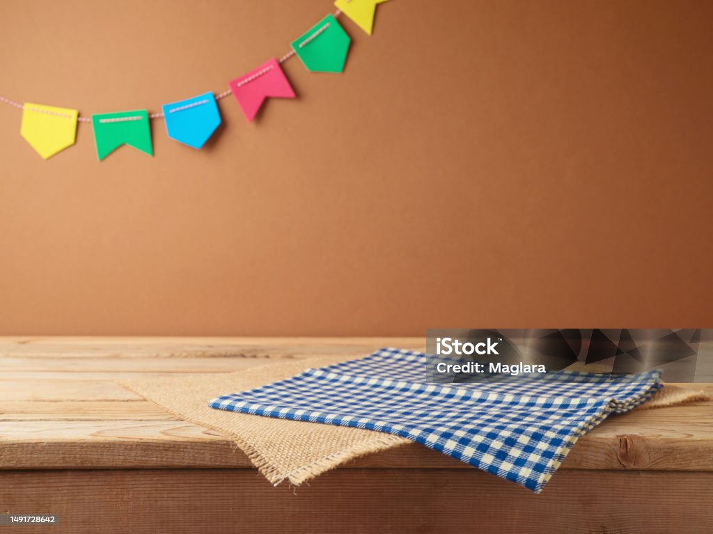Brazilian Festa Junina summer harvest festival concept. Empty wooden table with tablecloth over wall  background. Mock up for design and product display Table Stock Photo