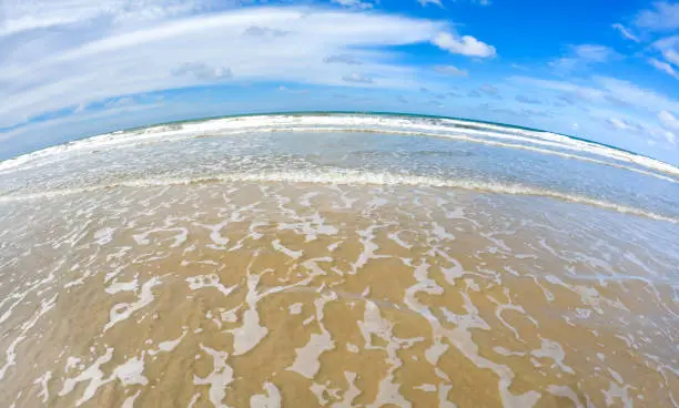 Fish-eye view on tropical beach and ocean.waves and blue sky in the background.