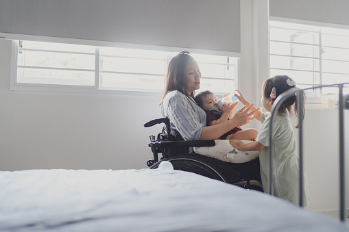 Beyond disability - Disabled Asian Chinese woman spends time with her two children in the bedroom