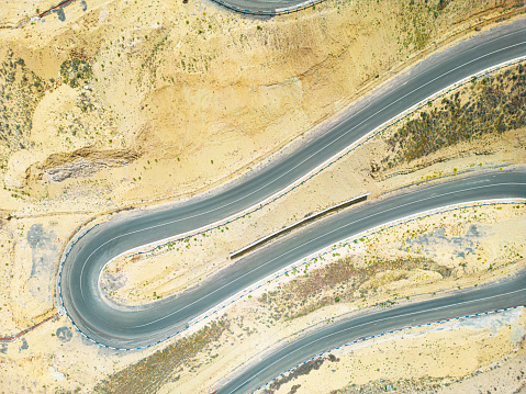 Top aerial view of snake curved road.  Winding mountains road. View from above. Driveway serpentine with cars