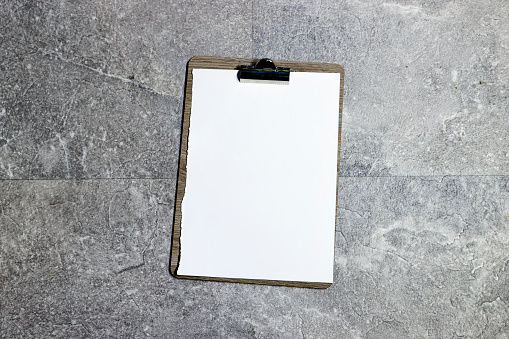 Classic metal clipboard with blank white paper on grunge marble background