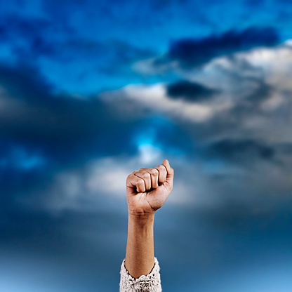 Female clenched fist against storm clouds.