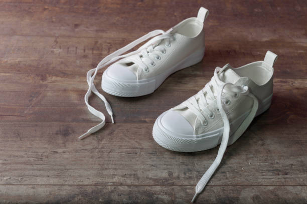 istock Children sneakers on a textured wood background. White. Copy space 1491745697