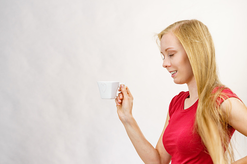 Blonde long hair woman with heart shaped coffee cup. Time to wake up, switching on. Copy space.
