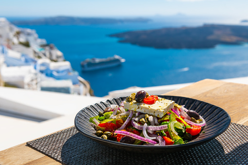 Greek salad with beautiful sea view in Santorini island, Greece. National greek cuisine concept. Travel and vacation