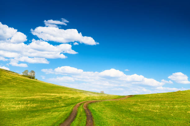 Green hills and the blue sky with clouds at spring sunny day. Country road in the hill. Beautiful nature background.