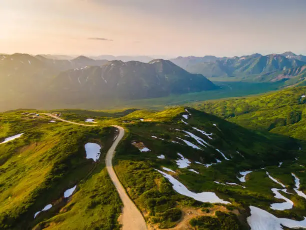 Green mountains with snow at sunset in Vilyuchinsky pass in Kamchatka, Russia. Aerial view. Beautiful summer landscape