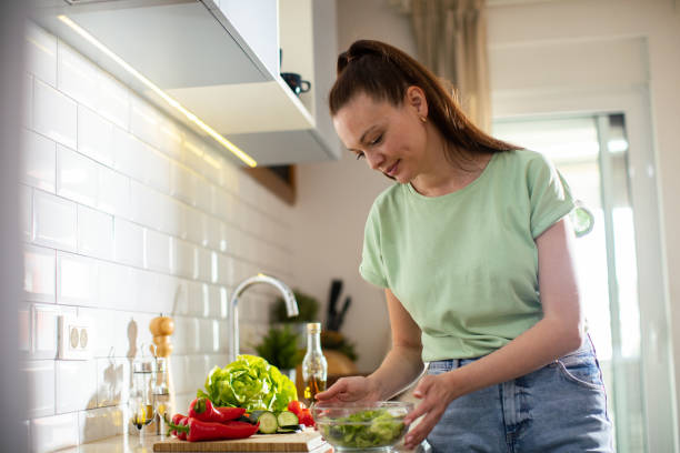 istock Young woman cutting and preparing vegetables in a kitchen at home 1491751939