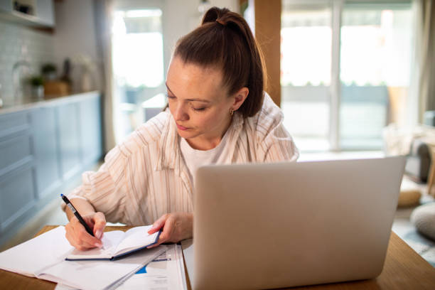 istock Young woman going over her finances at home while using her laptop 1491752501