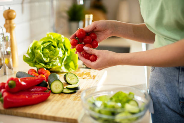 istock Young woman cutting and preparing vegetables in a kitchen at home 1491752949