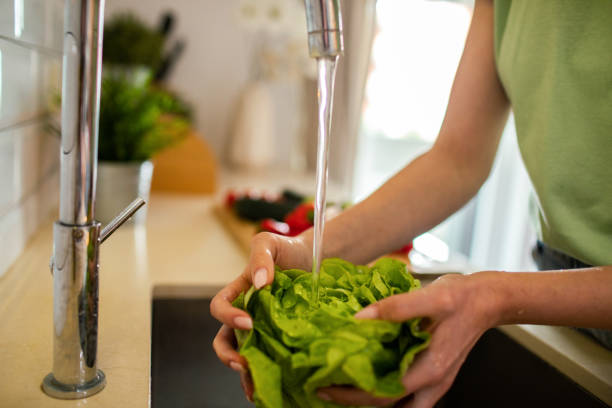 istock Young woman washing and preparing vegetables in the kitchen 1491752974