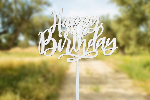 happy birthday wooden text concept near blurred olives field
