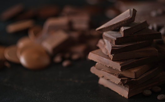 Closeup shot, of dark chocolate chunks on black background. Dessert food background.