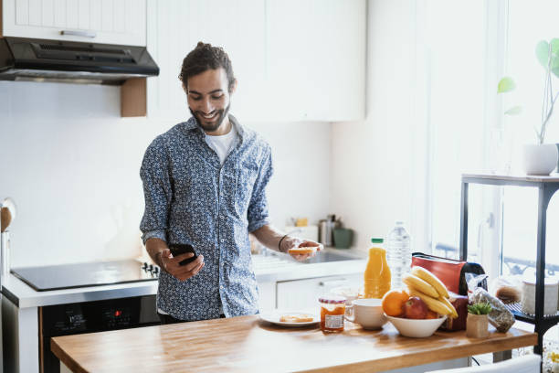 istock Mid adult multiracial man preparing breakfast at home and using smart phone 1491764954