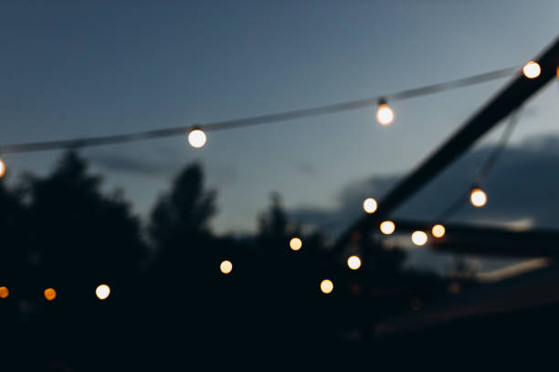istock Decorative outdoor string lights at night time, Defocused Background, night city life backdrop, party time with Yellow bokeh balls 1491767355