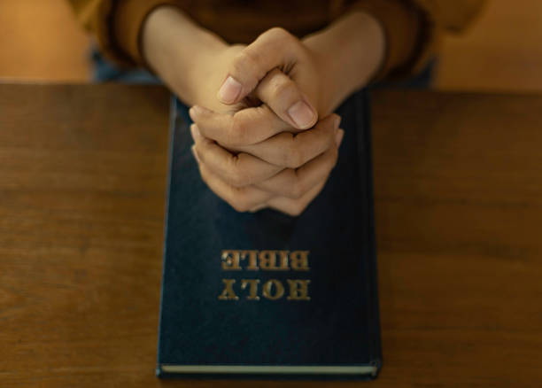 istock Woman Hands folded in prayer on a Holy Bible. 1491769058