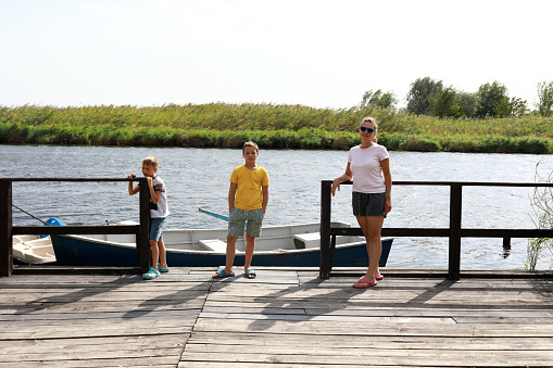 Mother with two her sons on river bank in summer