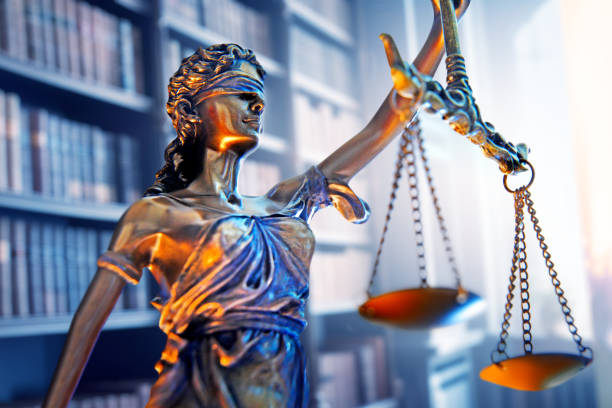 Lady Justice In Law Office Lady justice stands in a law office with a bookshelf of law books out of focus in the background. equal arm balance stock pictures, royalty-free photos & images