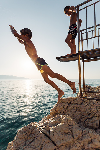 Two boys jumping from a diving platform and having fun on their summer vacation