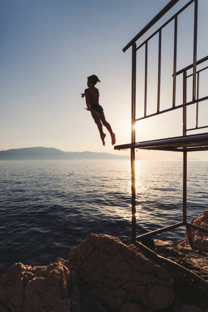 istock Silhouette of a boy jumping from a diving platform 1491779263
