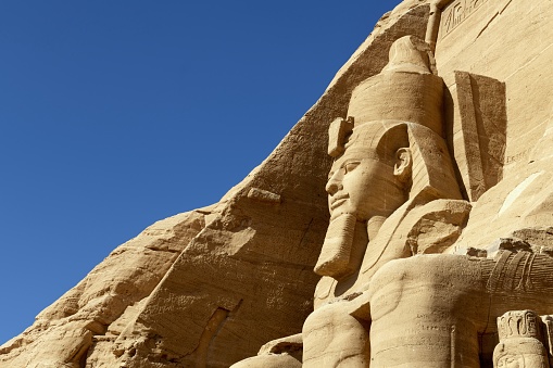 Abu Simbel, Egypt, April 13, 2023: Close-up of the leftmost statue at the temple of Rameses II in Abu Simbel on a sunny morning. The complex was relocated in its entirety in 1968 to higher ground to avoid it being submerged by Lake Nasser, the Aswan Dam reservoir.