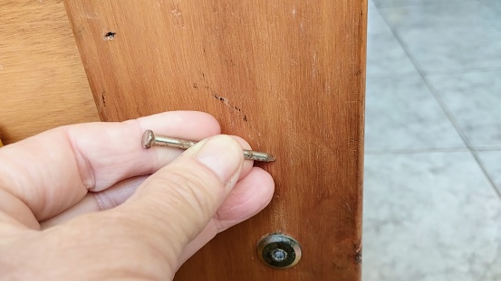 Nail in hand on wood