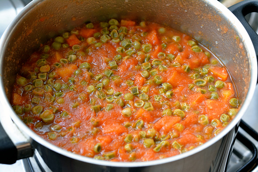 cooked slices of carrots and peas with tomato sauce, high in vitamins like vitamin A and vitamin C, some calcium minerals, and antioxidants that strengthen your immune system and high fiber content, selective focus