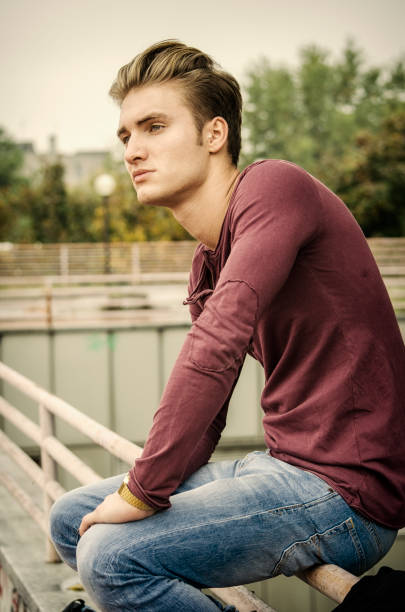 Handsome blond young man outdoors, looking away to a side
