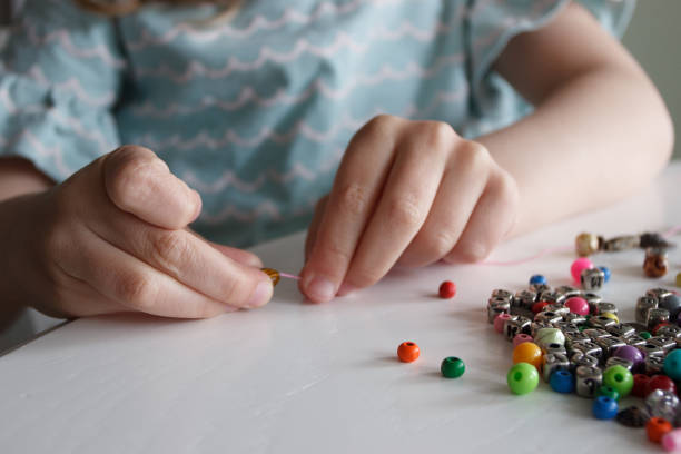 istock Process of making a bracelet from a thread and colored beads, concept of hobby 1491793612