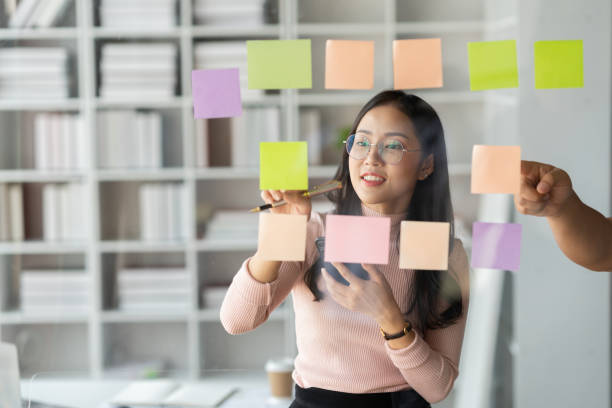 istock Asian businesswoman using mobile phone with pen to write on notepad business plan idea and find flaws to prevent mistakes in work. 1491794156