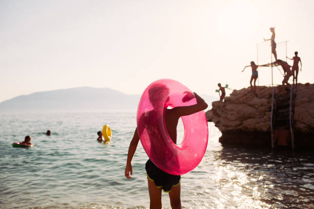 Silhouette of a boy on his summer vacation with inflatable ring entering in to the sea