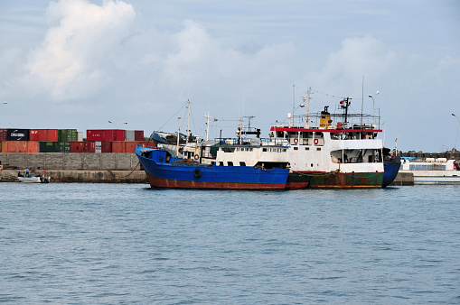 Moroni, Grande Comore / Ngazidja, Comoros islands: view of the commercial port with cargo containers and docked fishing trawler.