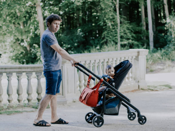 istock Caucasian young and handsome dad rolls his little daughter sitting in a stroller 1491812183