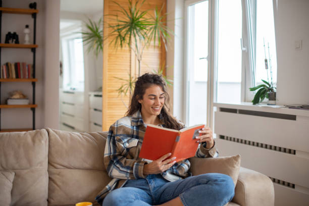 istock Happy woman reading book at home 1491822137