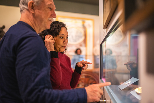Close up of a senior couple looking at the objects found at a Roman burial ground in an European city. Focus on the Hispanic woman. Looking away.