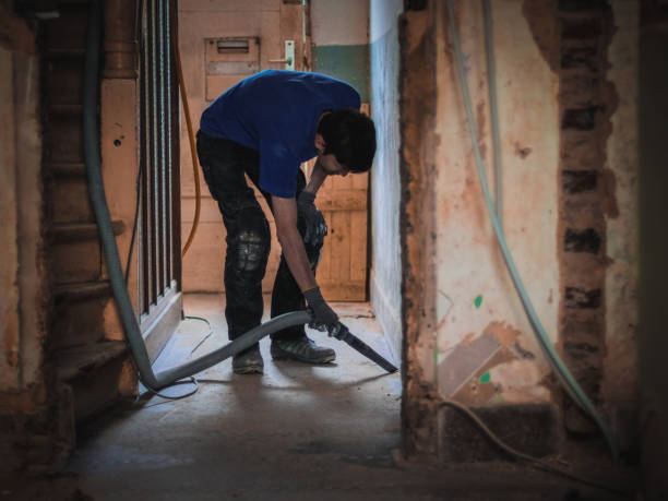 istock Caucasian young professional janitor in uniform vacuuming garbage with a construction vacuum cleaner 1491826336