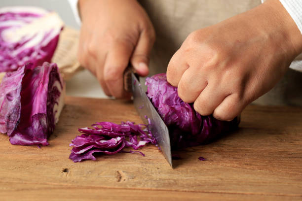 istock Female Slicing Purple Cabbage on Wooden Chopping Board 1491833195