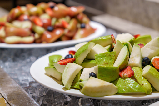 Slices of Jambu and Guava tropical fruits are served on a large plate along the buffet line.