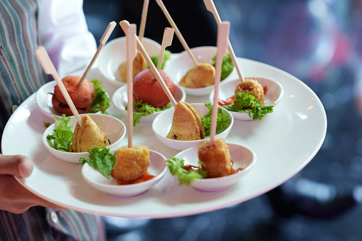 A waiter skillfully carries plates filled with finger food dishes at a festive event, party, or wedding reception.