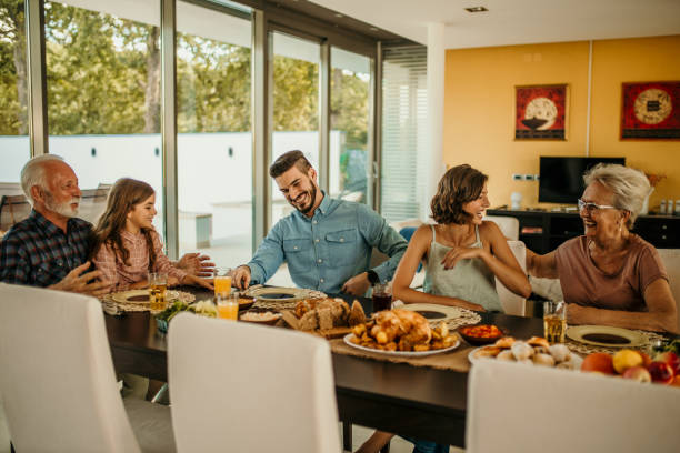 istock Happy extended family enjoying lunch at the dining table while the father is talking with a daughter 1491871205