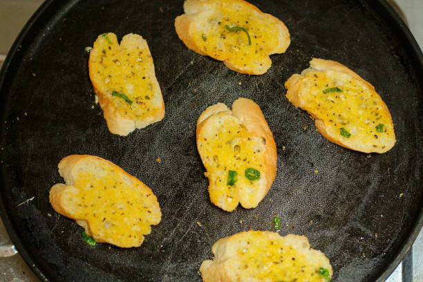garlic bread toasting on a black pan.
