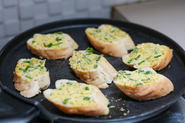 garlic bread toasting on a black pan.