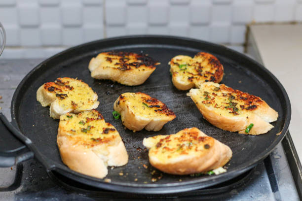 garlic bread toasting on a black pan.