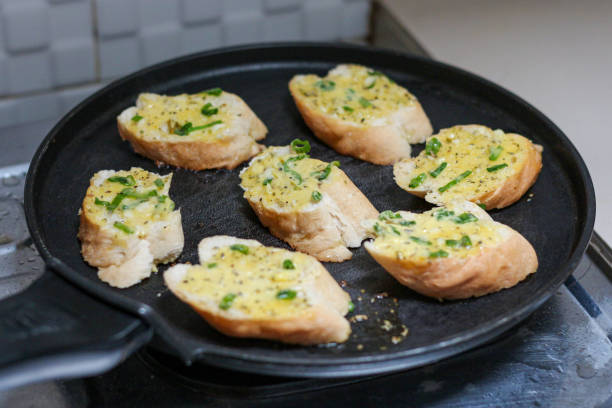 garlic bread toasting on a black pan.