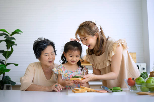 Grandmother, mother and granddaughter prepare food in the kitchen. stock photo